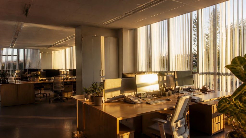 Bureau baigné par le soleil bas d'automne filtré par des stores à lamelles verticales